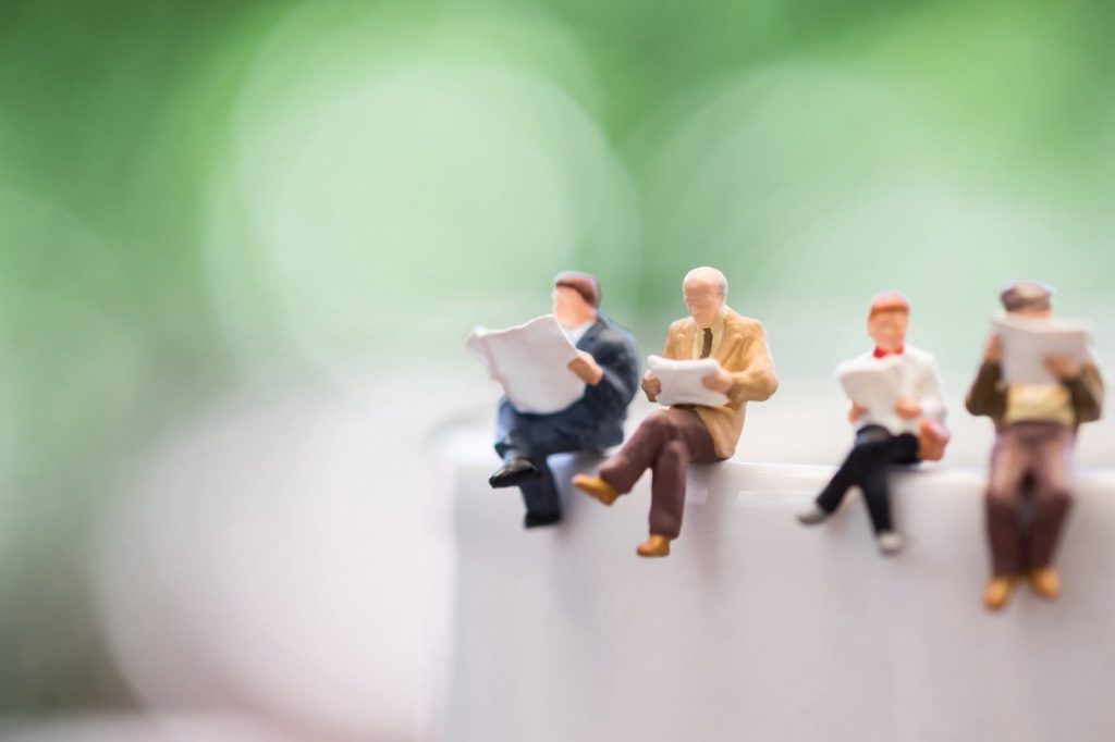 figurines of people reading a newspaper. News of the Blue Dolphin Store